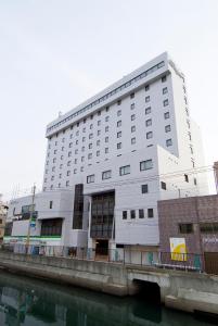 长崎Dormy Inn Nagasaki Shinchichukagai的一条大白楼,毗邻一条河流