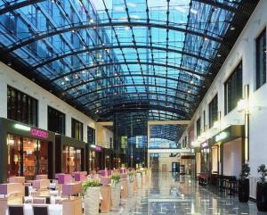 杜塞尔多夫玛丽蒂姆杜塞尔多夫酒店的一个带玻璃天花板和桌椅的购物中心