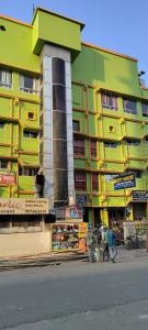 加尔各答Tusthi Banquets的一座黄色和绿色的建筑,前面的人在步行