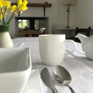 MorecombelakeUplands Garden的一张桌子,上面放着白咖啡杯和汤匙