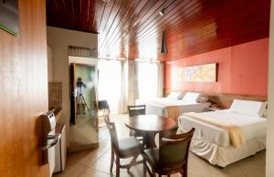 巴纳内拉斯Serra Golfe Apart Hotel的一间设有两张床和一张桌子及椅子的房间