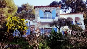 昂蒂布Magnifique "Gite de la Garoupe" au Cap d'Antibes à 300m des plages的白色的房子,拥有蓝色的窗户和树木