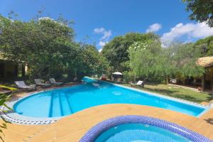 皮帕巴西热带村酒店的一个带椅子和树木的大型蓝色游泳池