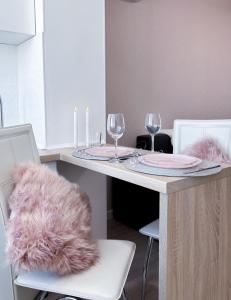 哈尔科夫Радужная студия на Южном вокзале的餐桌,配有两杯玻璃和粉红色毛绒枕头
