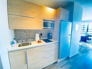 圣胡安KASA Starfish by the Sea - 8th floor Studio Apt for 2 BALCONY Ocean City View的厨房配有木制橱柜和蓝色冰箱。
