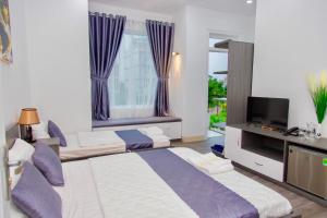 Kinh DinhRoyal Hotel Ninh Thuận的一间卧室设有两张床、一台电视和一扇窗户。