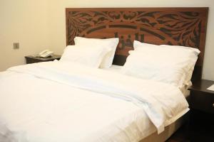 塔伊夫Al Khuzama Resort的一张配有白色床单和木制床头板的大床
