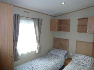 布德Bude Coastal Lodge的一间卧室设有两张床和窗户。