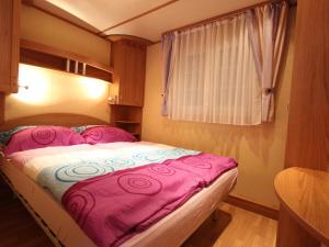圣卡尼兹Mobile home near Lake Klopeiner See的小卧室配有一张带粉色毯子的床