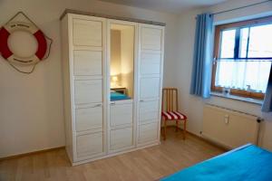 达默Kajüte 5的卧室内的白色衣柜,配有一张床和窗户