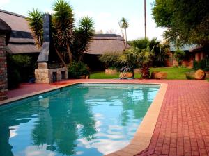 克龙斯塔德Boskoppie Lion & Tiger Reserve的一座带砖砌车道的庭院内的游泳池
