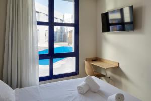 洛格罗尼奥Iraipe Logroño Hotel的一间卧室设有一张床和一个带游泳池的窗户