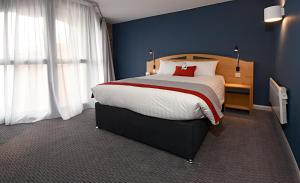利物浦快捷假日利物浦阿尔伯特码头酒店的一间卧室设有一张大床和蓝色的墙壁
