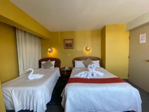 普诺Hostal Oscar Inn的两张床铺,位于酒店客房内,配有天鹅