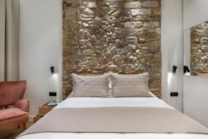 雅典J&A Luxury Residence的一间卧室设有一张大床和石墙