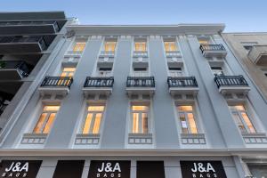 雅典J&A Luxury Residence的一座高大的白色建筑,设有窗户和阳台