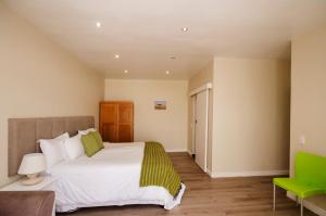 布鲁堡史特兰Small Bay Guest House的一间卧室配有一张大床和一张绿色椅子