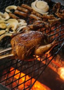 PujunganKAMPUNG KOPI CAMP的烤架上的鸡,有一大堆食物