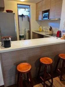 普孔PUCON HOUSE - Lake Access & Near Ski Center的厨房配有带2把凳子的柜台和冰箱。