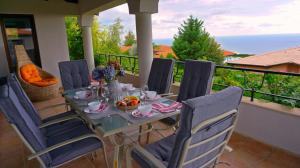 巴尔奇克Вила Афина - Villa Afina的阳台上的桌椅,上面有饭