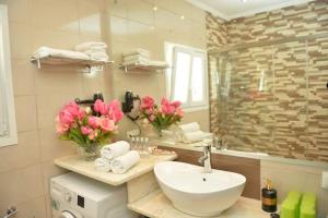帕莱欧卡斯提撒angela panorama的浴室设有水槽、镜子和粉红色的鲜花