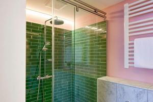 明斯特Central Hotel Münster的浴室铺有绿色地铁瓷砖,配有淋浴。