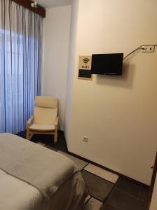 阿威罗Aveiro Theater Rooms的一间卧室配有一张床、一把椅子和电视。