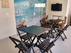 瓜鲁雅Suíte Sanlubia Enseada Guarujá的一间带2张桌子和椅子的用餐室以及电视