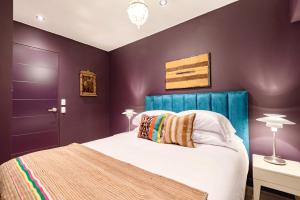利马✶ Maras Residence ✶ LUXURY Rooftop Pool & Grill的一间卧室设有紫色的墙壁和一张带蓝色床头板的床