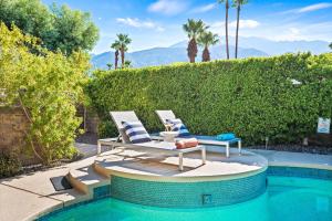 棕榈泉California Dreamin'的一个带两把椅子和一张桌子的庭院,毗邻一个游泳池