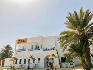 迈来亚CoZi Coliving space Djerba的前面有棕榈树的建筑