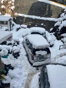 马拉里The Mad King's House & Cafe的雪覆盖的停车场,有雪覆盖的汽车