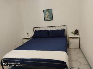 伊斯基亚casetta的卧室配有蓝色和白色的床和两张桌子