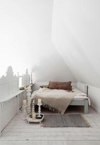 Hollerbusch的一间白色卧室,地板上配有一张床和蜡烛