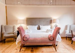 普利登堡湾Edenbrook Country Manor的一间卧室配有一张大床和两把椅子