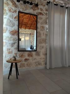 沃丽曼村Vigla Villas的石墙上的镜子,房间里的桌子