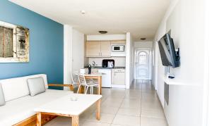 英格兰海滩普拉亚德索尔成人酒店的一间带白色沙发的客厅和一间厨房