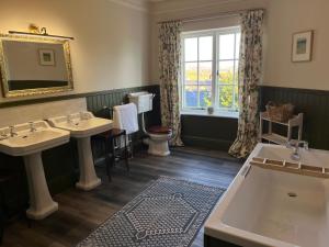 伍勒Yearle House的一间带两个盥洗盆、浴缸和窗户的浴室