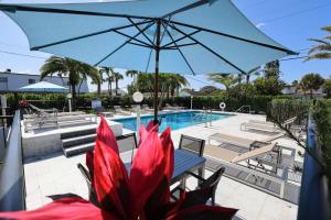 迪尔菲尔德海滩热带岛海滩度假村汽车旅馆的游泳池旁的桌椅上方的蓝色遮阳伞