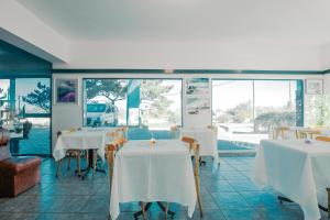 埃斯特角城Apart Hotel Punta Azul的餐厅设有白色的桌椅和窗户。