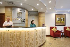 Kuala Belait圣淘沙酒店的站在酒吧的男人和女人