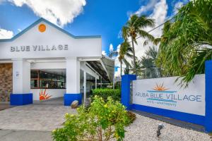 棕榈滩阿鲁巴蓝村公寓酒店的一座带有蓝村标志的建筑