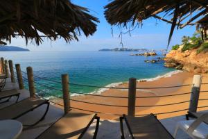 阿卡普尔科Suites Torres Gemelas VIP的享有带椅子和蚊帐的海滩美景