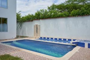 吉拉尔多特Casa vacacional Girardot 5 habit的白色墙壁前的游泳池