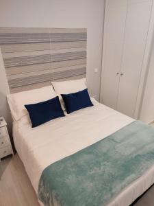 马德里Estudio Madrid Norte 2的卧室配有带蓝色枕头的大型白色床