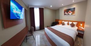 Batu MerahGrand Avira Hotel的一间酒店客房,配有一张床和一台电视