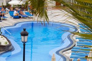 洛斯克里斯蒂亚诺斯Beverly Hills Suites - Excel Hotels & Resorts的棕榈树旁的游泳池边有街灯