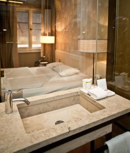 慕尼黑科尔提娜酒店的一间带水槽的浴室,配有一张位于后面的床