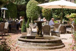 温彻斯特温彻斯特文酒店的花园中的喷泉,人们坐在桌子上