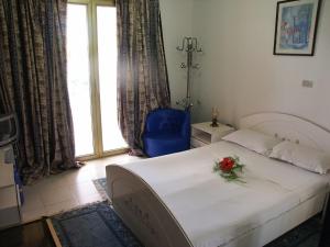 哈马马特汉密尔顿酒店的一间卧室配有一张床、一把蓝椅和一个窗户。